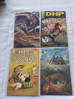 Four comic books laid out on white cloth, each in clear plastic sleeve to protect condition.