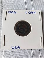 Front side of the 1906 Indian Head 1 Cent coin in protective holder showing the Indian chief's head design and handwritten notes.