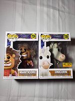 Front view of the two Funko Pop figures in their original boxes showing Manticore (#724) and Unicorn (#725) characters from Onward movie. Unicorn is labeled Hot Topic exclusive.