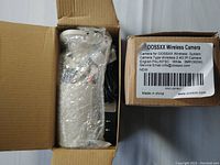 Pair of OOSSXX wireless cameras still in original packaging with label showing specifications.