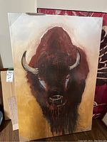 Full view of buffalo painting on canvas showing frontal portrait of the buffalo with detailed horns and texture on the surface.
