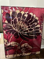Full frontal image of the framed floral artwork showing stylized flower in dark and beige tones on red background with lacquered high gloss surface.