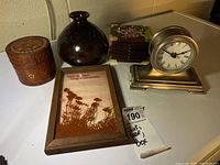 Photo showing the clock, vase, three decorative boxes and framed floral art on a surface