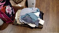 Box of folded boys clothing items including shirts and pants stacked on top