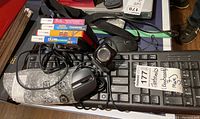 Photo showing Dell wired keyboard, wired mouse wrapped in bubble wrap, and Nintendo DS game cases stacked on top.