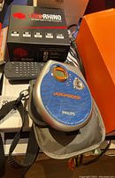 Photo showing Philips Jogproof portable CD player in its carrying case, Red Rhino entertainment box, and remote control on a table.