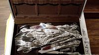 Box of stainless steel flatware consisting of various utensils with ornate decorative handles