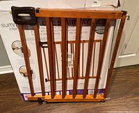 Wooden Summer Infant safety gate leaning against its original box showing full gate structure and packaging.