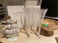 Two boxes and four frosted champagne flutes from Millennium Collection displaying years, wood bowl, and decorative ship