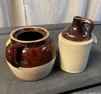 Photo of antique stoneware bean pot without lid and matching jug side by side on black surface.