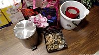 Wide view showing all items including metal garbage can, white bucket with pots, decorative stones basket, faux flower, and tote bag.