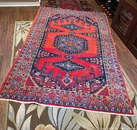 Full view of the Asian style area rug placed on another patterned rug, showing the full size and overall color scheme and pattern.