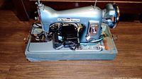 Full side view of the blue Modern Home sewing machine in its case showing the machine body and foot pedal.