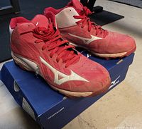 Pair of used red and white Mizuno baseball running shoes on Mizuno box, showing front and side views with visible wear