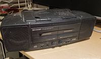 Front left angle of the Sharp WD CO 88 stereo with visible dust and wear, showing cassette and CD compartments and speakers.