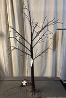 Full view of the plastic tree with attached lights standing upright showing height and structure.