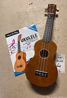 Photo showing the ukulele and beginner's guide booklet on a textured surface.