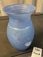 Front view of light blue opaque glass vase with wide flared mouth and rounded body.