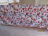 Full view of the Kantha quilt displayed over a wooden rail showing Birds in Paradise pattern on white background.