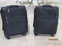 Front view of two black carry-on spinner suitcases with zippered compartments and spinner wheels