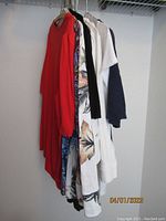View of nine Chico's tops hanging on a rack showing a range of colors and patterns.