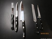 Full set of two Cutco cutters, one Cutco fork, and two Wusthof Dreizack knives on black background