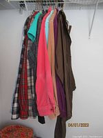 View of hanging shirts including four corduroy and several plaid L.L. Bean shirts along with brown rain coat.