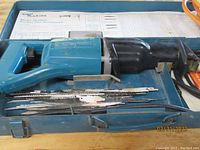 Makita JR3000V reciprocating saw in blue with multiple saw blades laid out in metal case.