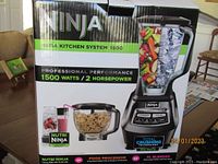 Photo of Ninja Mega Kitchen System 1500 box showing branding and key features: 1500 watts, 2 horsepower, total crushing technology, includes Nutri Ninja cup, food processor, and XL blender.