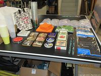 View of the entire assortment on table including coasters, napkins, cups, candles, tote bag, and utensils.
