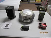 Overview of all items: Sony CD radio cassette recorder, voice recorder case and manual, tuner in packaging, heater box and manual on table.