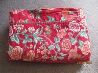 Folded red floral fabric presumably one of the tablecloths or runners in the lot