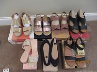 Seven pairs of women's shoes arranged in two rows on the floor showing various brands and styles.