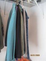 Five women's sweatshirts and zip-ups hanging on hangers showing various colors and styles