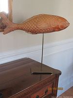 Side view of wooden fish sculpture elevated on metal stand, showing full length and scale detail