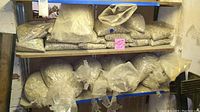 Two shelves filled with multiple sealed clear plastic bags containing assorted aquarium gravel of various sizes and colors, mainly gray and beige tones.