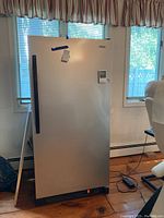 Full front view of silver upright freezer in room setting