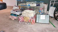 Lot of linens arranged on floor, showing multiple folded and packaged items including king size sheets and curtains