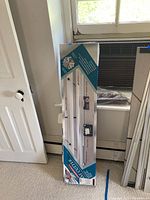 Photo of the Logan Intermediate Model 450 mat cutter in its original box, positioned against a wall near a window and door.