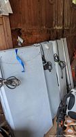 Three electric plant light fixtures stacked vertically. Fixtures are coated with speckled grey paint and have cords coiled on top.