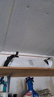 White metal halide plant light fixture with power cord on a shelf with cleaning sprays below.