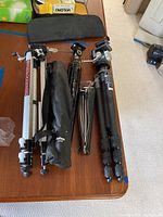 Group of four tripods arranged on table, showing overall lot contents
