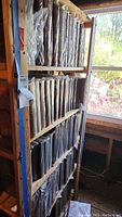 Three-tier wooden shelf holding approx. 10–12 leather-bound volumes per shelf, wrapped in plastic.
