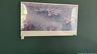 Front view of framed Monet poster hanging on wall, showing the title strip and artwork.