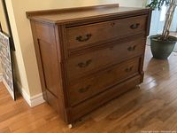 Front angled view of chest showing three drawers and metal bail pulls