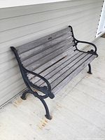 Front and right-side view of bench showing cast iron ends, armrests, and weathered wooden slats on seat and backrest.