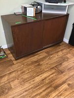 Front view of wooden storage cabinet with sliding doors and five drawers on the left side.