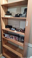 Wood shelf with multiple camera items including cameras, flash units, and audio player