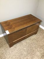 Full view of wooden cedar lined chest showing shape and wood finish wear