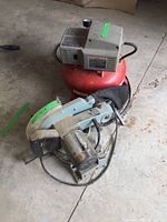 Delta compound miter saw and Porter Cable air compressor together on concrete floor showing overall condition and wear